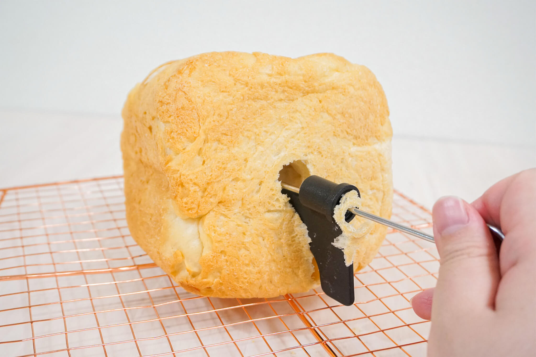 パン羽根取り棒を使って食パンに埋まったパン羽根を取り除いている様子