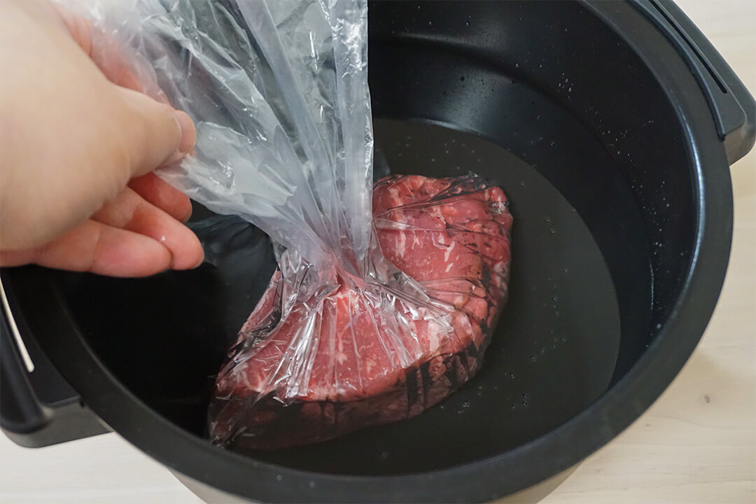 牛肉が入った袋を水が入ったホットクックの内釜に沈めている様子