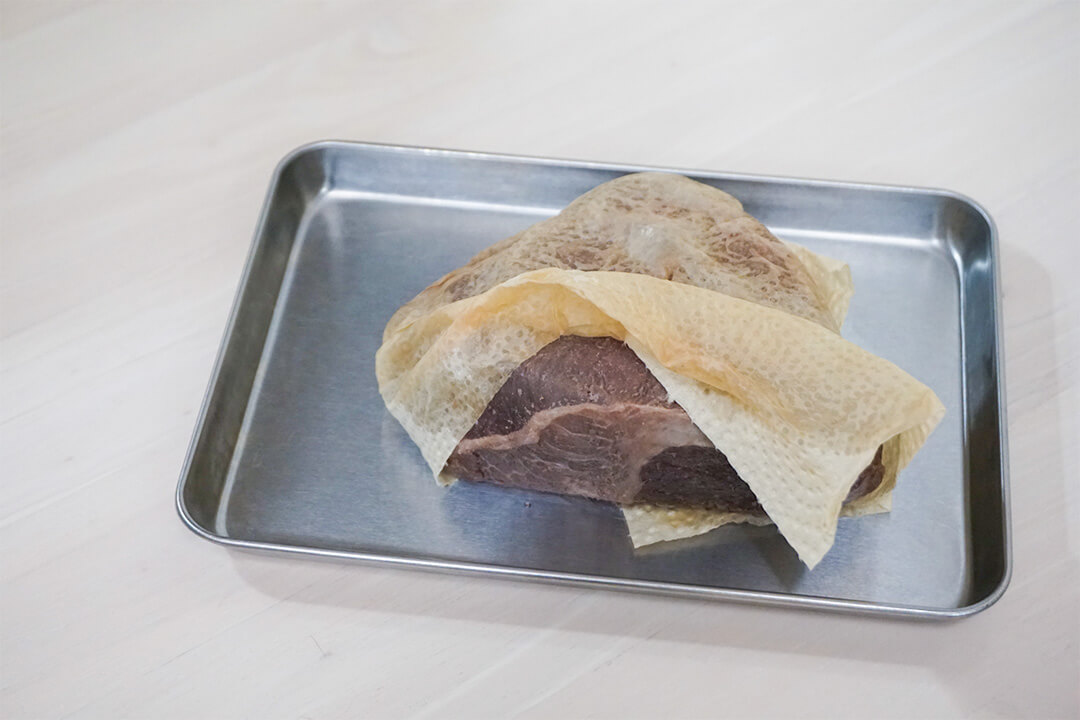 調理後のローストビーフの肉汁をペーパータオルで拭いている様子