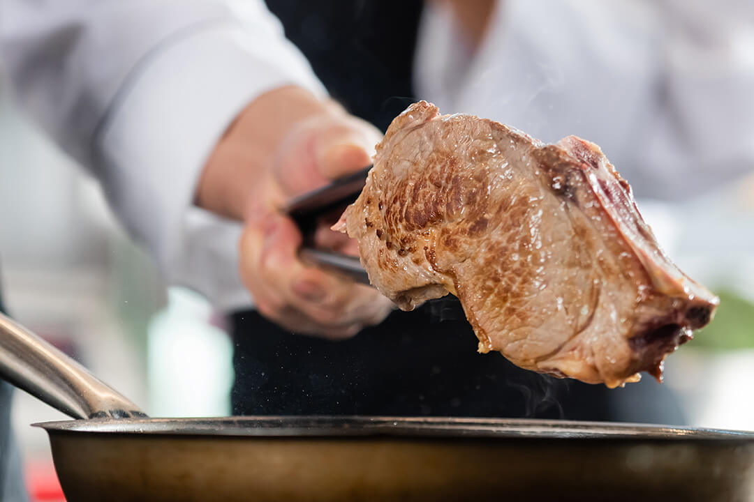 かたまり肉にフライパンで焼き目をつけている様子